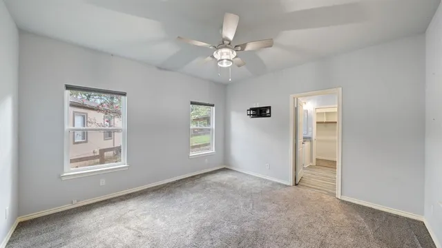 an empty room with windows and fan