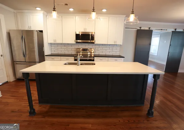 a kitchen with stainless steel appliances wooden floor sink refrigerator and microwave