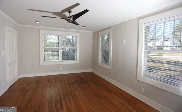 a view of an empty room with wooden floor and a window