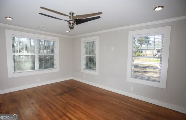 a view of an empty room with wooden floor and a window