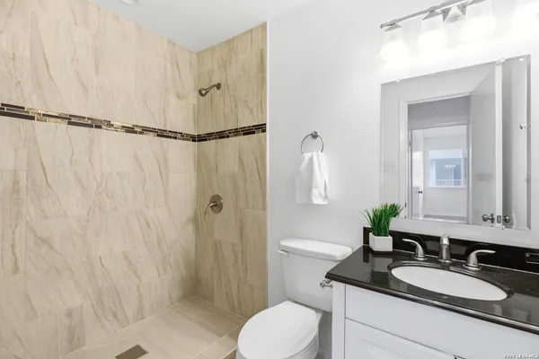 a bathroom with a granite countertop sink mirror vanity and toilet