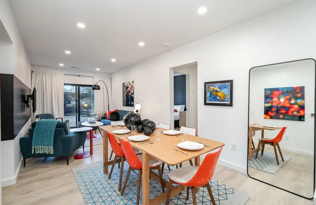 a kitchen with stainless steel appliances kitchen island a table chairs in it and wooden floors