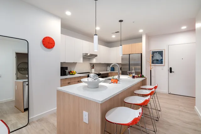 a kitchen with stainless steel appliances kitchen island granite countertop a stove a sink a refrigerator and chairs