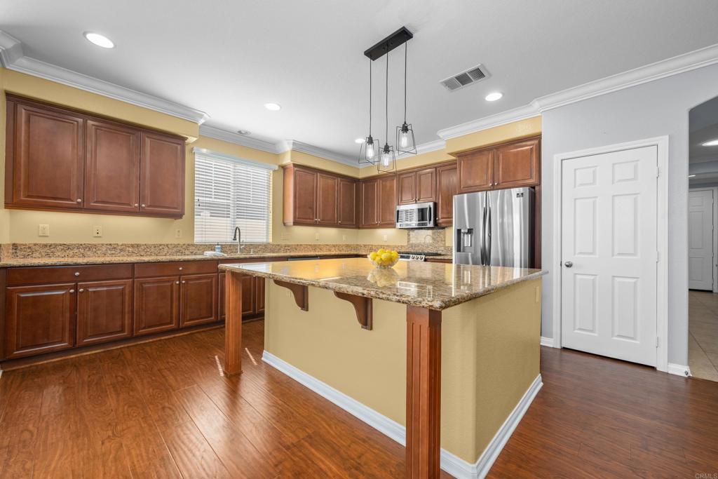 40296 Pasadena Drive Temecula, CA 92591 - Photo 6 of 36 a kitchen with stainless steel appliances granite countertop a refrigerator a sink dishwasher a stove and white countertops with wooden floor