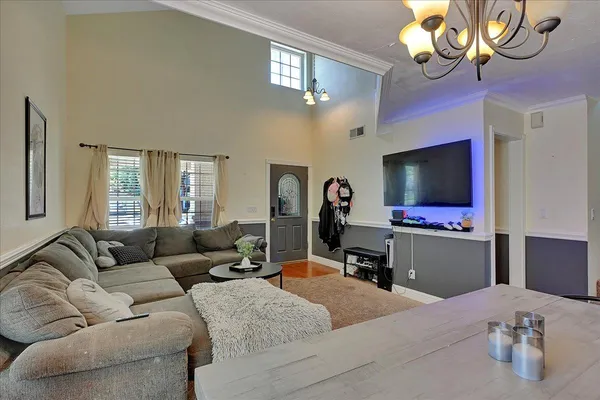 a living room with furniture a chandelier and a flat screen tv