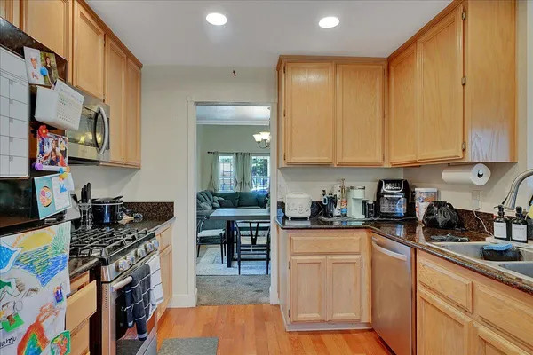 a kitchen with stainless steel appliances granite countertop a stove top oven a sink dishwasher and cabinets with wooden floor