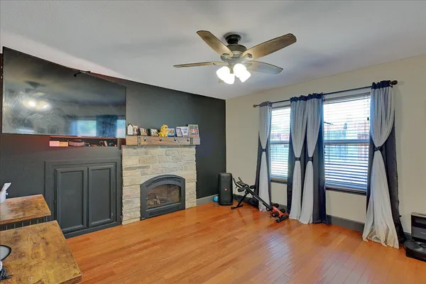 a view of a livingroom with a fireplace a ceiling fan and wooden floor