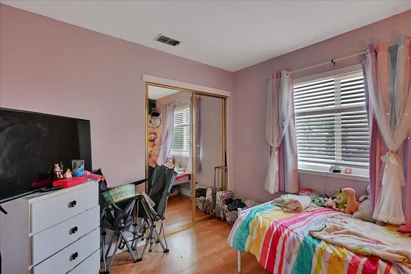 a bedroom with bed and a flat tv screen on dresser