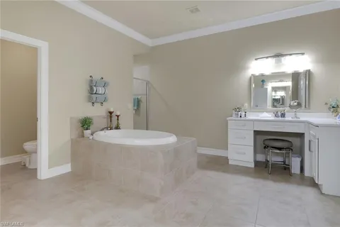 a spacious bathroom with a double vanity sink a toilet a mirror and bathtub