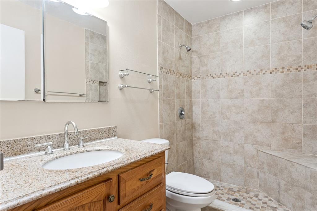 40 Moree Loop, Unit 7 Winter Springs, FL 32708 - Photo 16 of 31 a bathroom with a granite countertop sink a toilet a mirror and shower