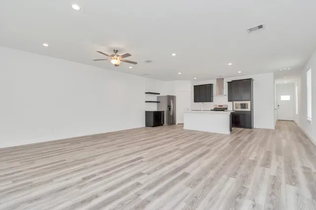 a large kitchen with stainless steel appliances a large counter top a stove and a refrigerator