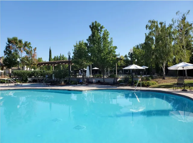 a view of a swimming pool with lawn chairs under an umbrella