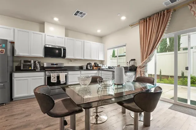 a kitchen with stainless steel appliances granite countertop a stove a refrigerator a kitchen island a stove a dining table and chairs with wooden floor