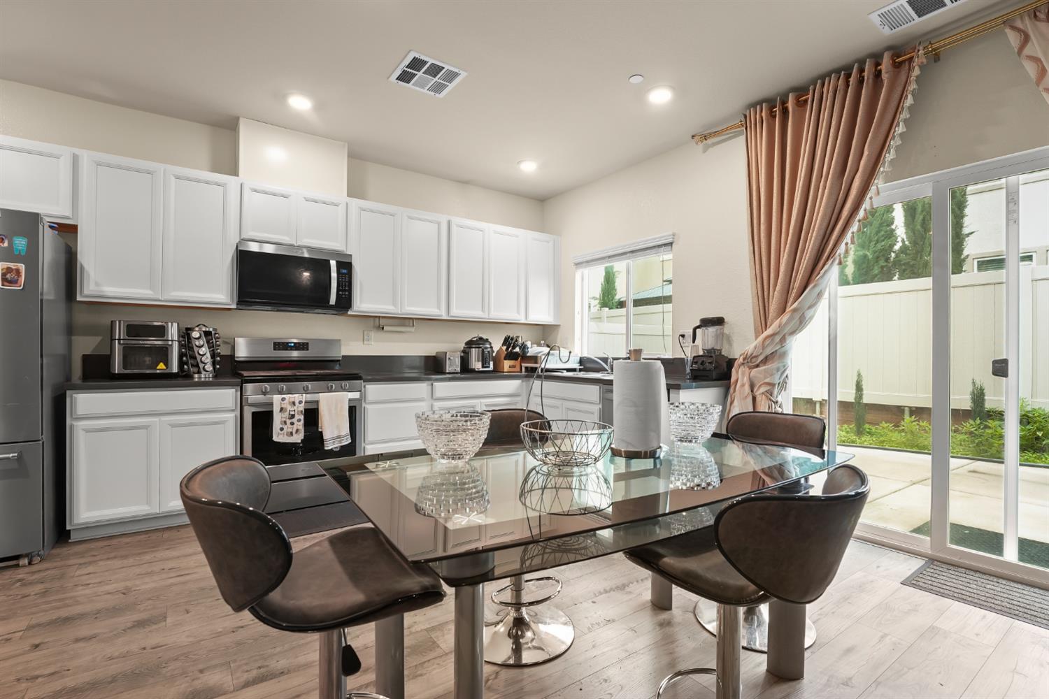 11789 Socrates Way Rancho Cordova, CA 95742 - Photo 4 of 23 a kitchen with stainless steel appliances granite countertop a stove a refrigerator a kitchen island a stove a dining table and chairs with wooden floor