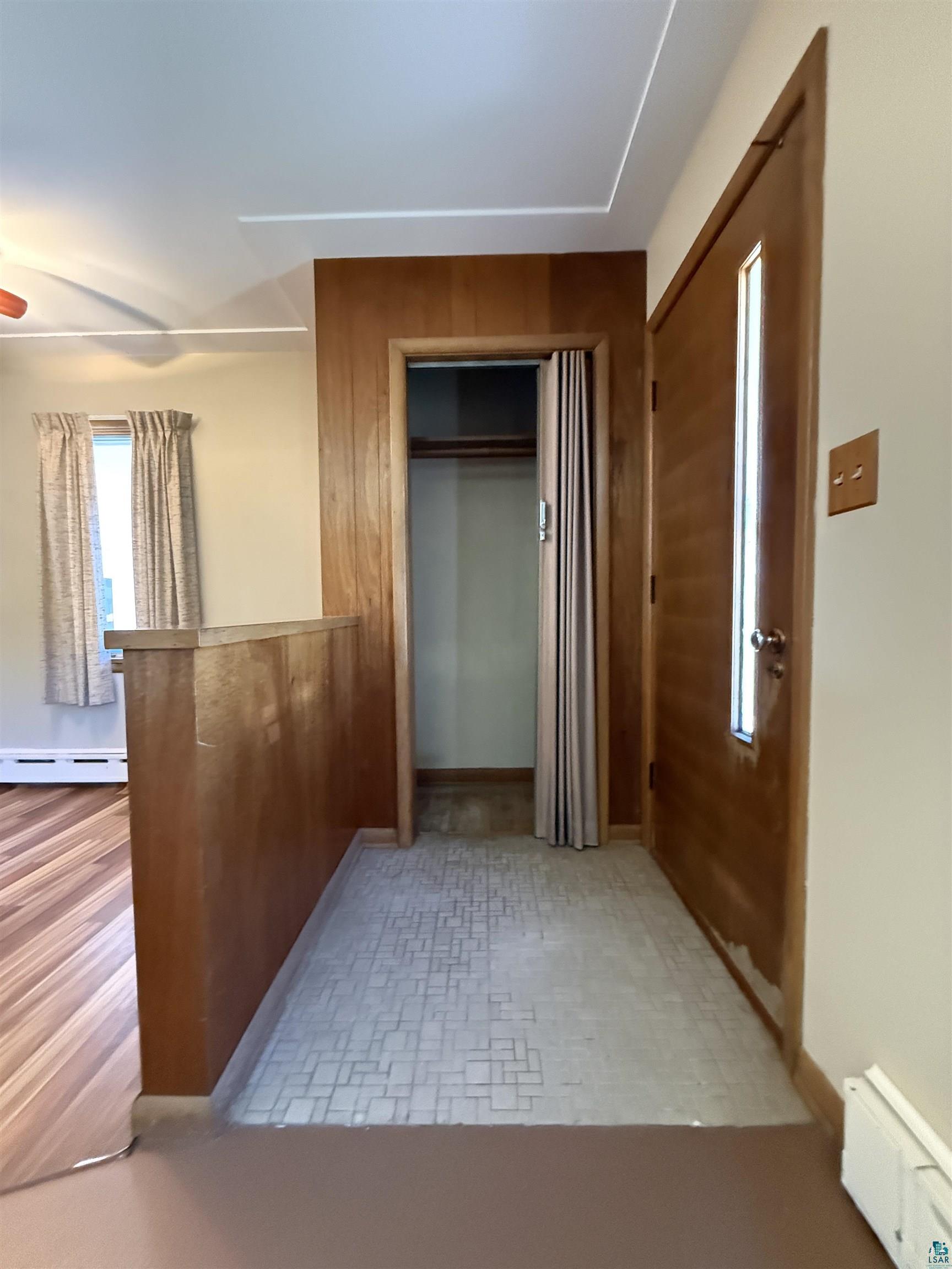 607 3rd Street Northeast Chisholm, MN 55719 - Photo 3 of 32 Entryway featuring wood-paneled walls, wood-finish flooring, and a closet with bifold doors