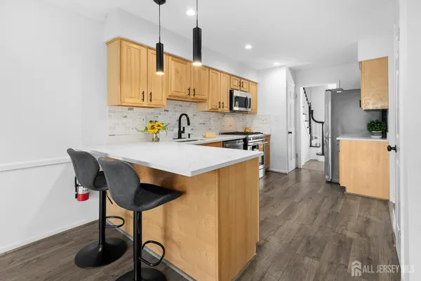 a kitchen with stainless steel appliances a stove a sink a refrigerator and wooden floor