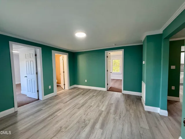 a view of an empty room with window and wooden floor
