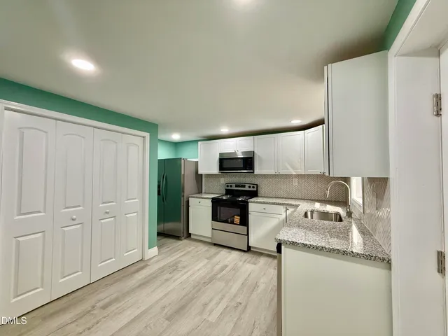 a kitchen with granite countertop a refrigerator stove and sink
