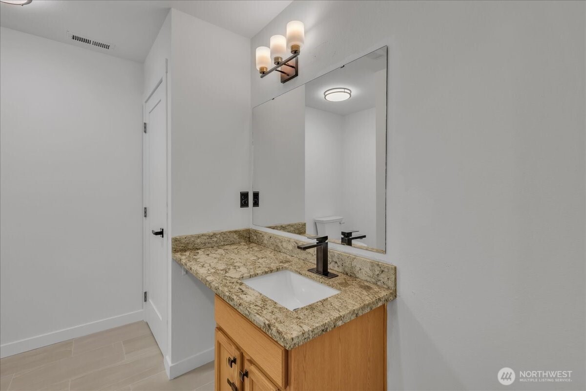 414 Easy Street Rainier, WA 98576 - Photo 28 of 38 a bathroom with a granite countertop sink and a mirror