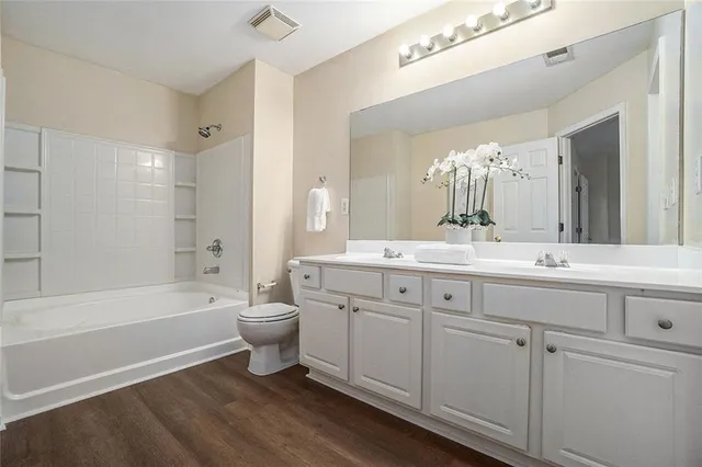 a bathroom with a double vanity sink toilet mirror and bathtub