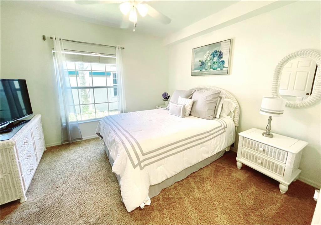 23821 Marbella Bay Road, Unit 102 Estero, FL 34135 - Photo 13 of 30 a spacious bedroom with a bed a couch and a window