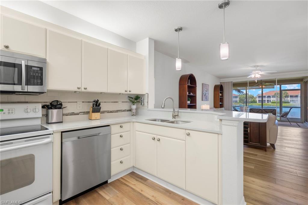 23821 Marbella Bay Road, Unit 102 Estero, FL 34135 - Photo 3 of 30 a kitchen with granite countertop a sink cabinets stainless steel appliances and wooden floor