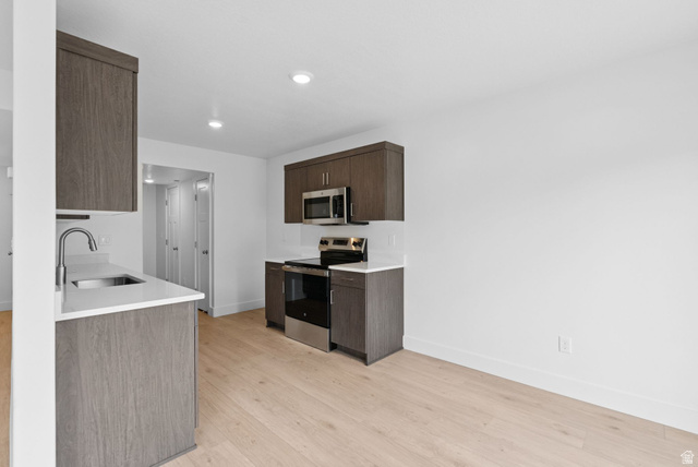 1617 North Angel Street Layton, UT 84041 - Photo 21 of 43 Kitchen with appliances with stainless steel finishes, dark brown cabinetry, light wood-type flooring, recessed lighting, and light stone counters