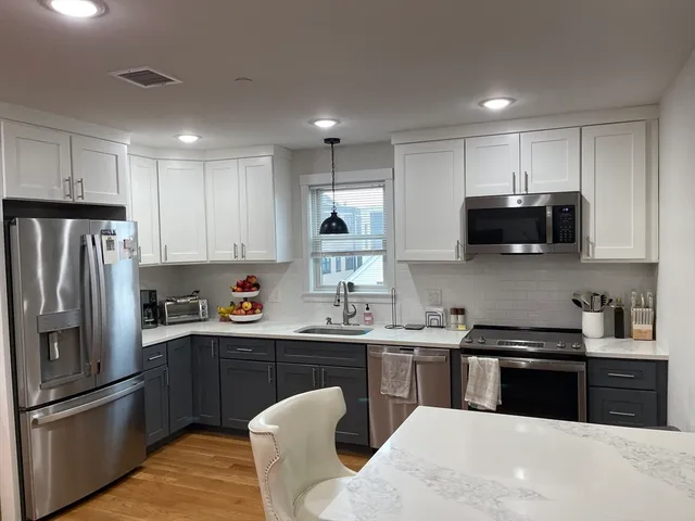 a kitchen with stainless steel appliances granite countertop a sink a stove a refrigerator and cabinets