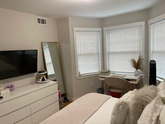 a bedroom with a bed and a flat tv screen on the dresser