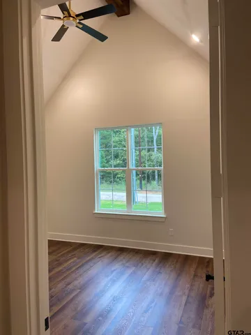 an empty room with wooden floor closet and windows