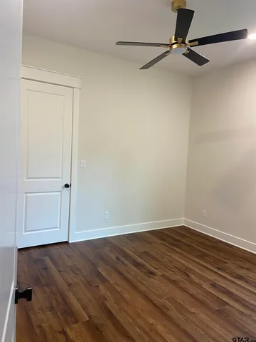 a view of room with hardwood floor and a ceiling fan