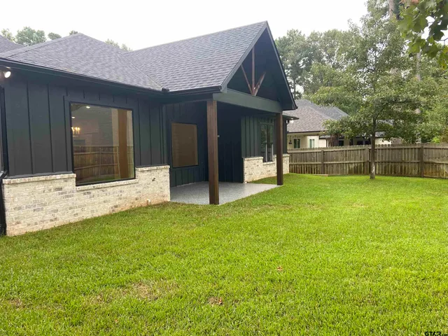 a view of a house with a yard and a large tree