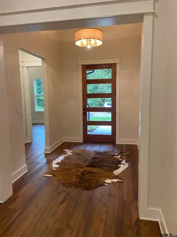 a view of an empty room with window and wooden floor
