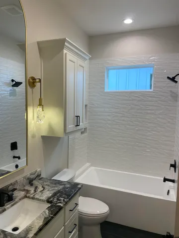 a bathroom with a granite countertop sink toilet and shower