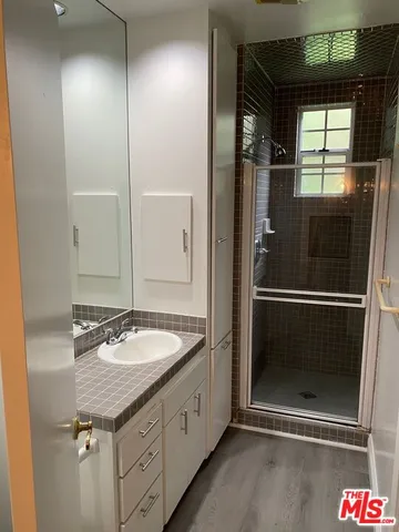 a bathroom with a granite countertop sink a mirror and shower