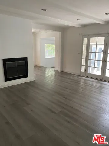 a view of an empty room with glass door and wooden floor