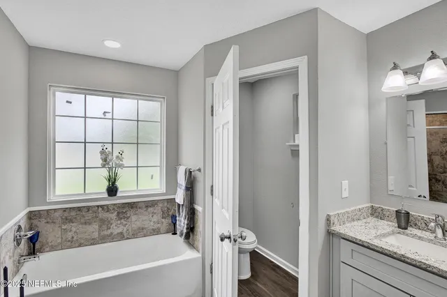 a bathroom with a granite countertop tub sink and mirror
