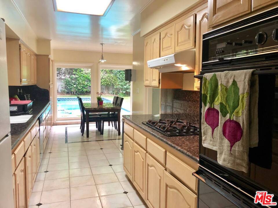 9601 Heather Road Beverly Hills, CA 90210 - Photo 3 of 17 a kitchen with stainless steel appliances granite countertop a stove a sink and a microwave