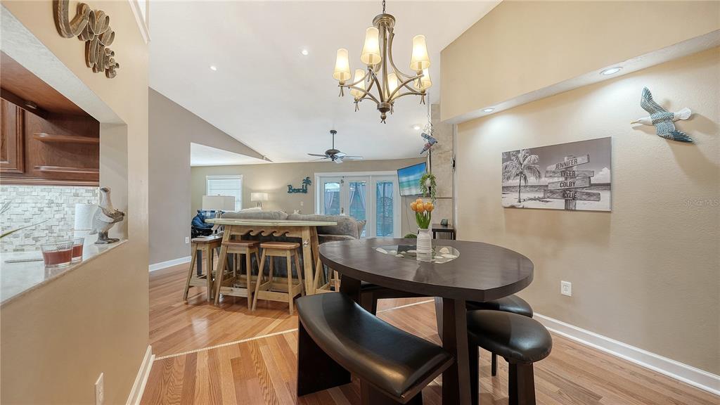 5968 Rachele Drive Sarasota, FL 34243 - Photo 15 of 55 a dining room with wooden floor a chandelier a wooden table and chairs