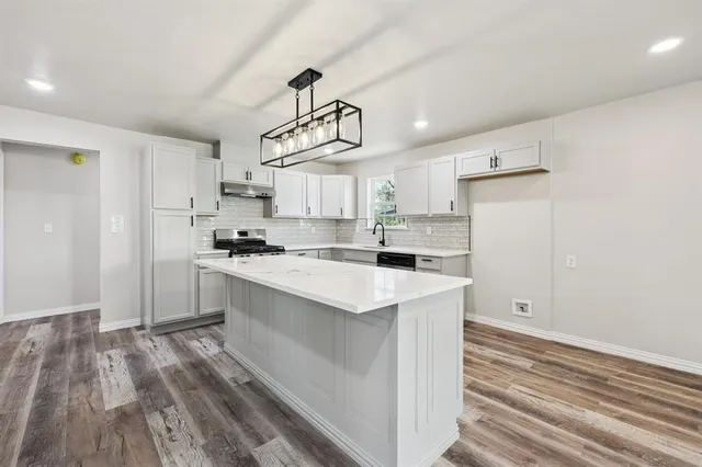 a kitchen with kitchen island a sink wooden floor and white appliances