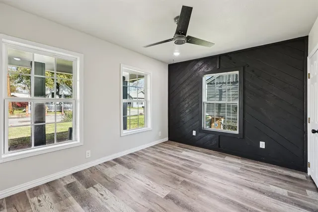 a view of an empty room with a window and wooden floor