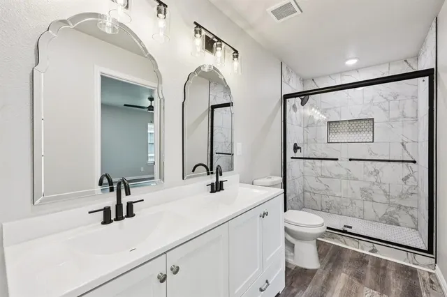a bathroom with a double vanity sink mirror and toilet