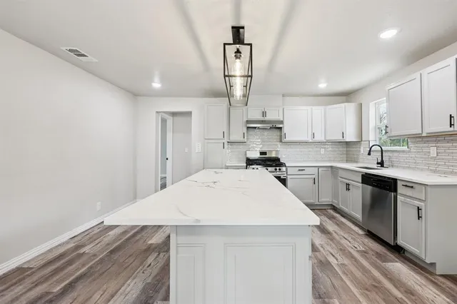 a kitchen with granite countertop a sink stainless steel appliances and cabinets
