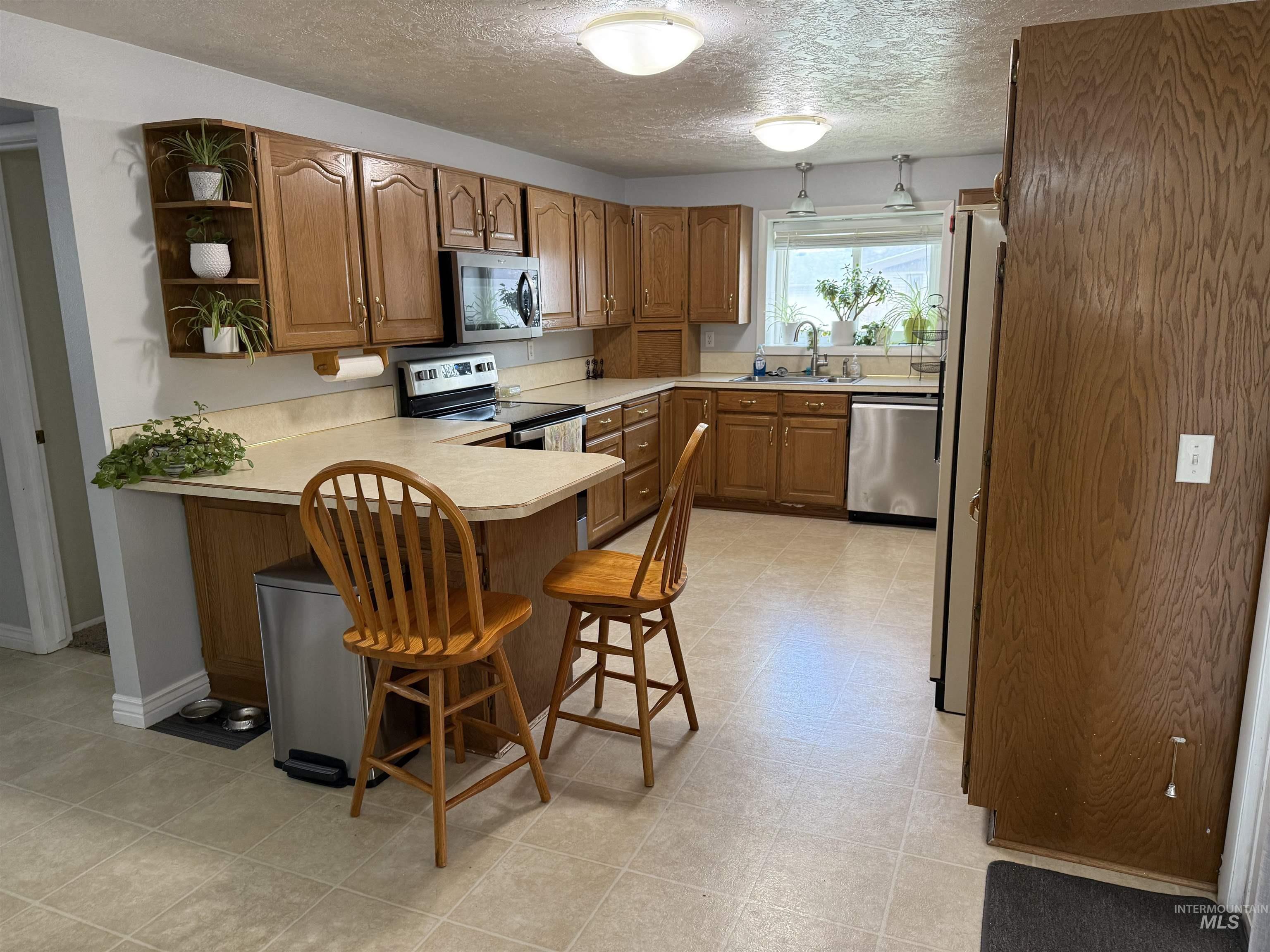 4926 Easy Street Chubbuck, ID 83202 - Photo 19 of 29 Kitchen with brown cabinets, light countertops, open shelves, a kitchen breakfast bar, and a peninsula