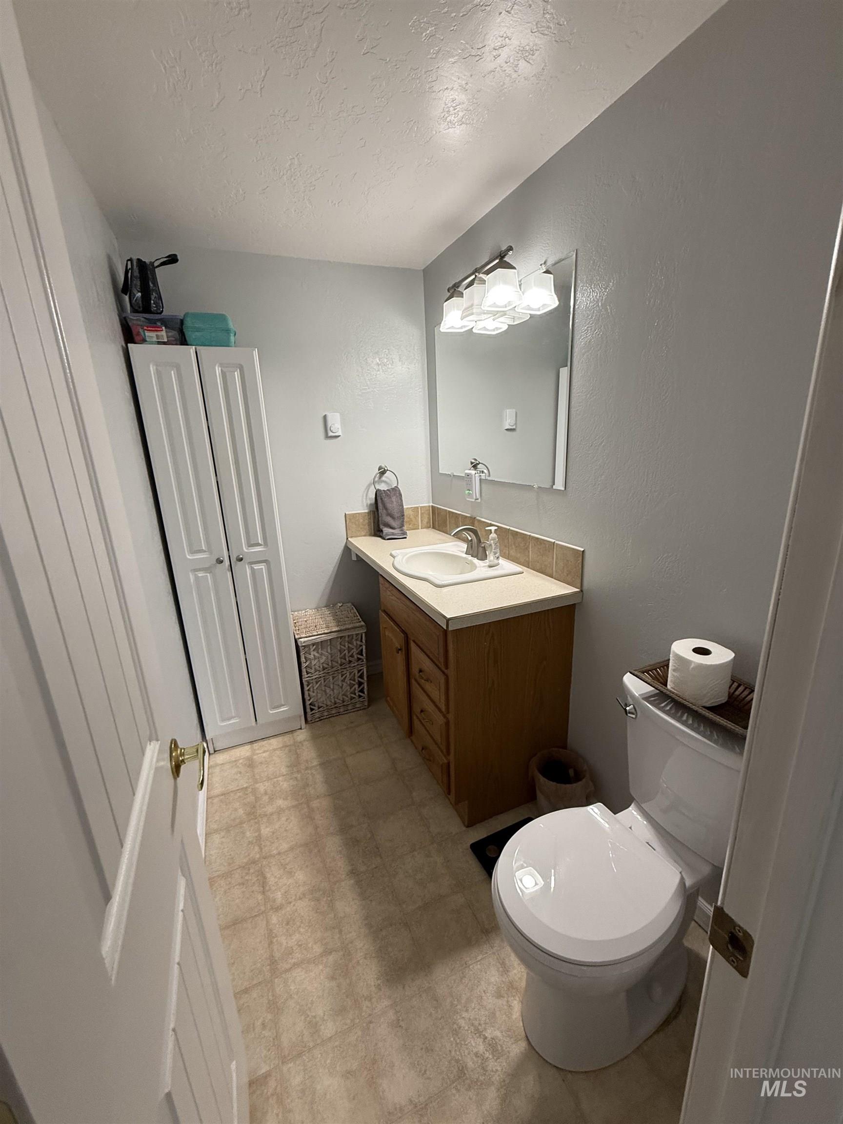 4926 Easy Street Chubbuck, ID 83202 - Photo 2 of 29 Half bath featuring a textured ceiling, vanity, light floors, and a textured wall