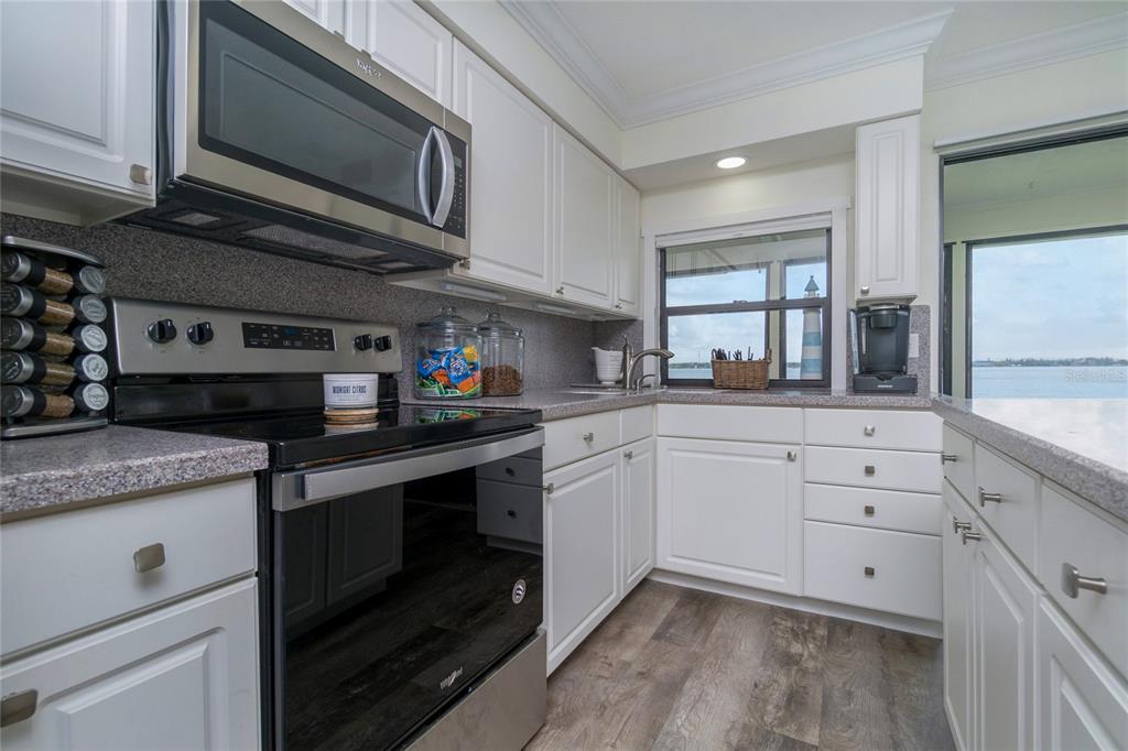 5041 North Beach Road, Unit 3A AND 3B Englewood, FL 34223 - Photo 37 of 52 a kitchen with stainless steel appliances granite countertop a stove a sink and a microwave