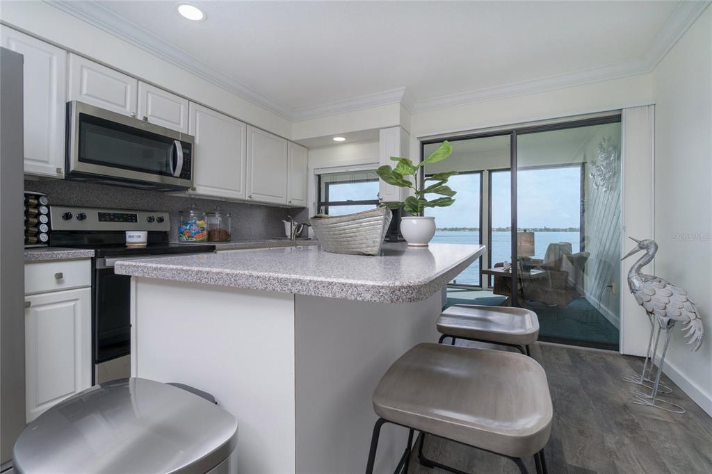 5041 North Beach Road, Unit 3A AND 3B Englewood, FL 34223 - Photo 39 of 52 a kitchen with stainless steel appliances granite countertop a sink dishwasher stove top oven a dining table and chairs with wooden floor