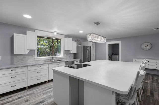 a kitchen with granite countertop a stove a sink dishwasher and a refrigerator with wooden floor