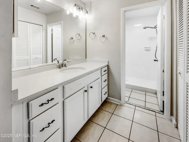 a spacious bathroom with a double vanity sink a mirror and a shower