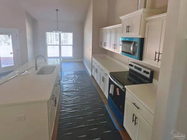a kitchen with white cabinets and window